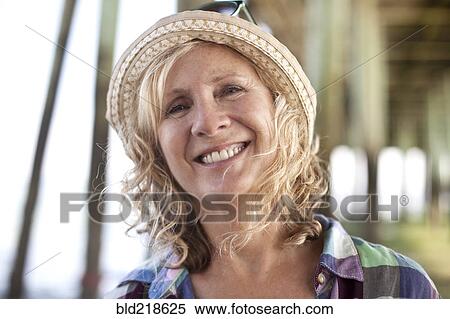 Stock Photography - Caucasian woman standing under boardwalk on beach. Fotosearch