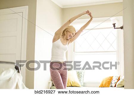 Caucasian woman stretching in bedroom View Large Photo Image Stock Photo - Caucasian woman stretching in bedroom. Fotosearch