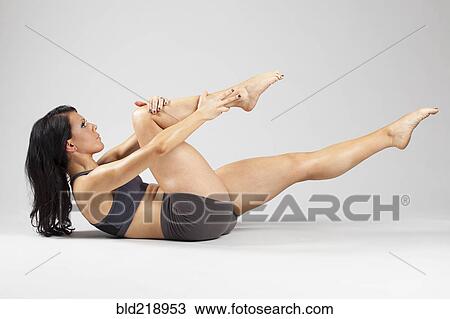 Stock Image - Caucasian woman stretching leg on floor. Fotosearch