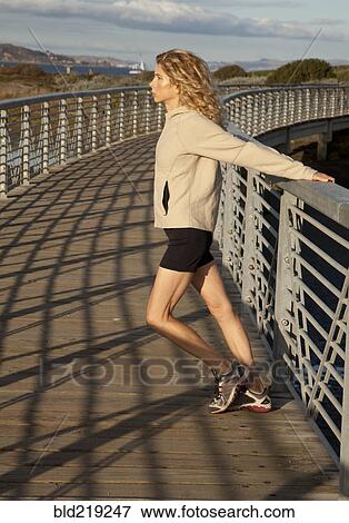 Caucasian woman stretching on footbridge View Large Photo Image Stock Photo - Caucasian woman stretching on footbridge. Fotosearch