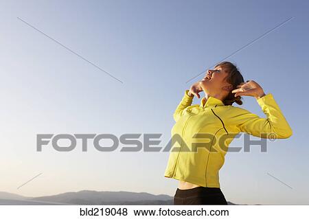 Stock Photo - Caucasian woman stretching under blue sky. Fotosearch