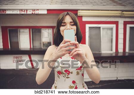 Stock Image - Caucasian woman taking selfie with cell phone. Fotosearch