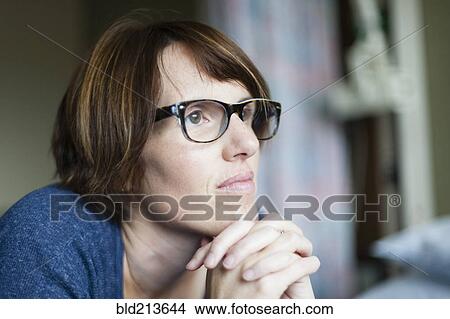 Picture - Caucasian woman thinking with hands clasped. Fotosearch