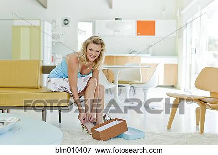 Caucasian woman trying on shoes in living room View Large Photo Image Stock Photo - Caucasian woman trying on shoes in living room. Fotosearch