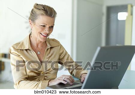 Stock Image - Caucasian woman typing on laptop. Fotosearch