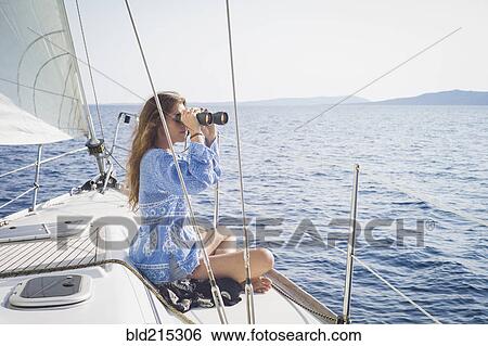 Stock Photograph - Caucasian woman using binoculars on boat deck. Fotosearch