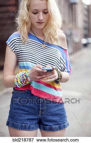 Stock Photo - Caucasian woman using cell phone on city sidewalk. Fotosearch