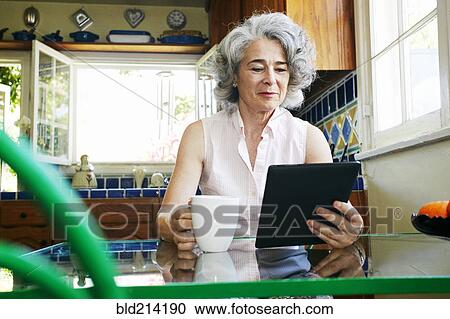 Caucasian woman using digital tablet in kitchen View Large Photo Image Stock Image - Caucasian woman using digital tablet in kitchen. Fotosearch