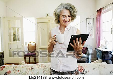 Caucasian woman using digital tablet in living room View Large Photo Image Stock Photo - Caucasian woman using digital tablet in living room. Fotosearch