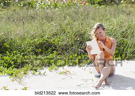 Caucasian woman using digital tablet on beach View Large Photo Image Stock Image - Caucasian woman using digital tablet on beach. Fotosearch