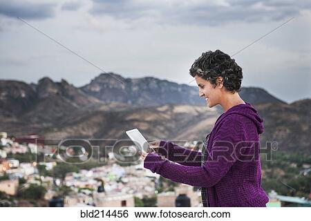 Stock Photograph - Caucasian woman using digital tablet on rooftop. Fotosearch
