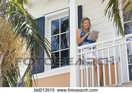 Caucasian woman using digital tablet on balcony View Large Photo Image Stock Photography - Caucasian woman using digital tablet on balcony. Fotosearch