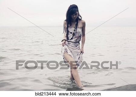 Picture - Caucasian woman wading in water on beach. Fotosearch