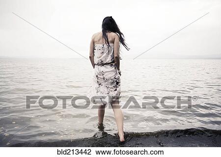 Caucasian woman wading in water on beach View Large Photo Image Stock Image - Caucasian woman wading in water on beach. Fotosearch