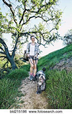 Caucasian woman walking dog on grassy hillside View Large Photo Image Stock Photograph - Caucasian woman walking dog on grassy hillside. Fotosearch
