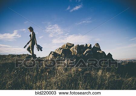 Stock Image - Caucasian woman walking in rural field. Fotosearch