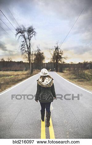 Caucasian woman walking on empty rural road View Large Photo Image Stock Photo - Caucasian woman walking on empty rural road. Fotosearch