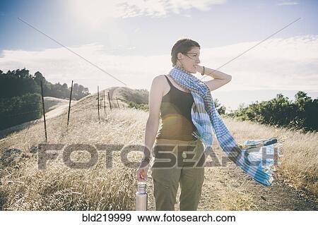 Stock Photo - Caucasian woman walking on rural dirt road. Fotosearch