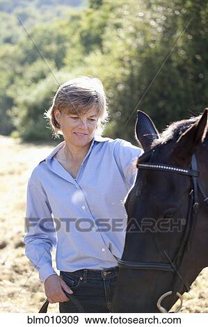 Caucasian woman watching horse View Large Photo Image Stock Photo - Caucasian woman watching horse. Fotosearch