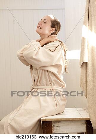 Stock Image - Caucasian woman wearing bathrobe in bathroom. Fotosearch