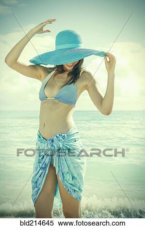Stock Photography - Caucasian woman wearing bikini and sun hat on beach. Fotosearch