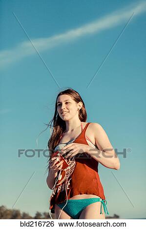 Stock Photograph - Caucasian woman wearing bikini under blue sky. Fotosearch