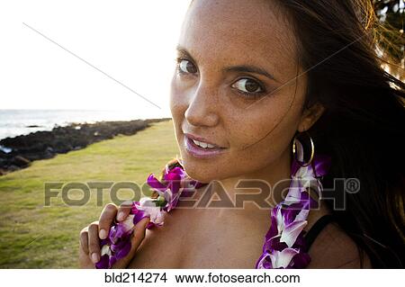 Picture - Caucasian woman wearing flower lei near ocean. Fotosearch