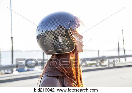 Stock Image - Caucasian woman wearing motorcycle helmet. Fotosearch