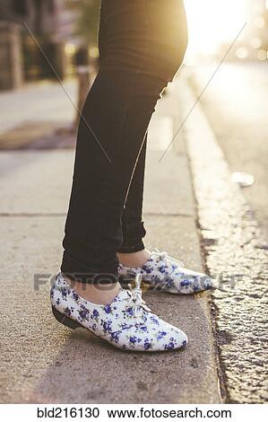 Stock Image - Caucasian woman wearing patterned shoes on city sidewalk. Fotosearch