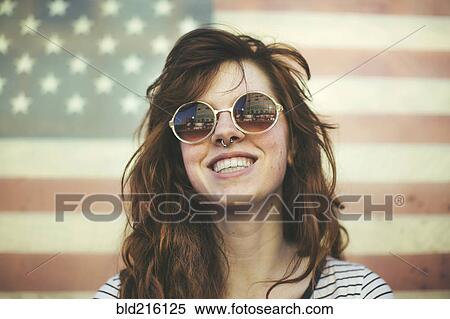 Stock Photography - Caucasian woman wearing sunglasses at American flag. Fotosearch