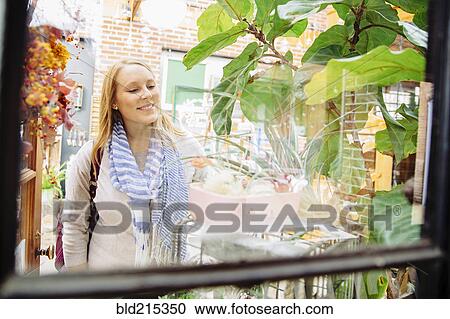 Stock Image - Caucasian woman window shopping in plant nursery. Fotosearch