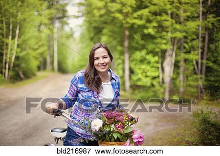 Stock Photo - Caucasian woman with bicycle on dirt road. Fotosearch