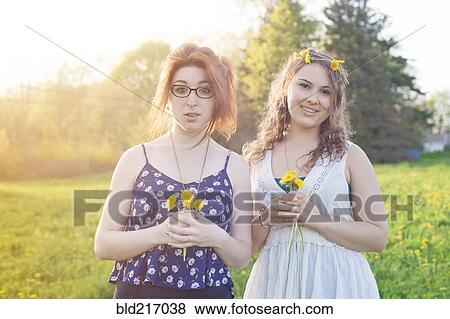 Stock Photo - Caucasian women holding flowers in field. Fotosearch