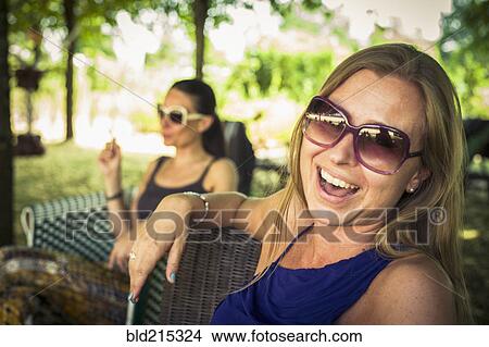 Picture - Caucasian women sitting in chairs in backyard. Fotosearch