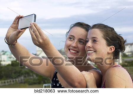 Stock Image - Caucasian women taking selfie with cell phone. Fotosearch