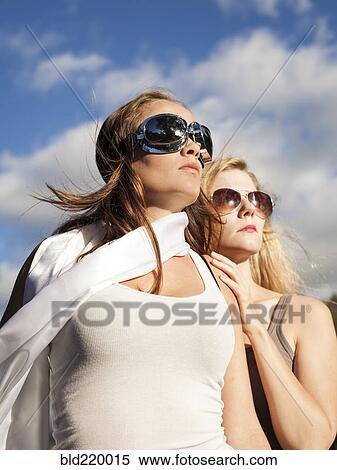 Stock Photography - Caucasian women wearing sunglasses and looking up. Fotosearch