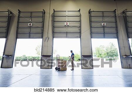 Stock Photography - Caucasian worker examining cardboard boxes in warehouse. Fotosearch