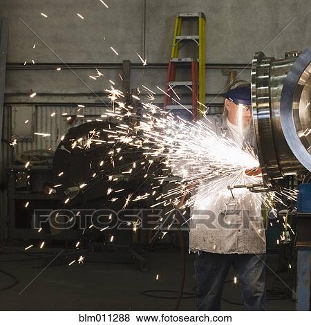 Stock Photo - Caucasian worker grinding metal in factory. Fotosearch