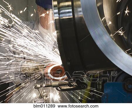 Caucasian worker grinding metal in factory View Large Photo Image Stock Photo - Caucasian worker grinding metal in factory. Fotosearch