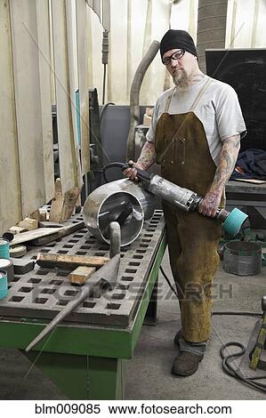 Stock Photography - Caucasian worker holding equipment in factory. Fotosearch