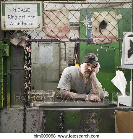 Stock Photo - Caucasian worker leaning on counter in factory. Fotosearch