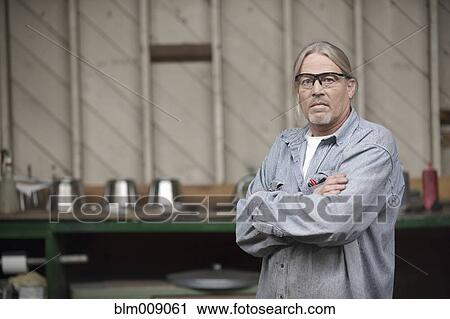 Stock Image - Caucasian worker standing in factory. Fotosearch