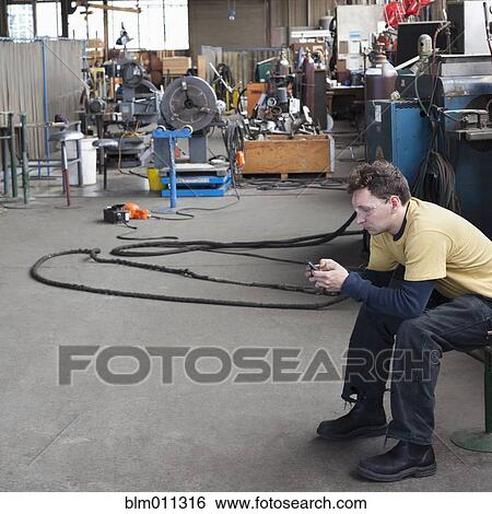 Caucasian worker text messaging on cell phone in warehouse View Large Photo Image Stock Photograph - Caucasian worker text messaging on cell phone in warehouse. Fotosearch