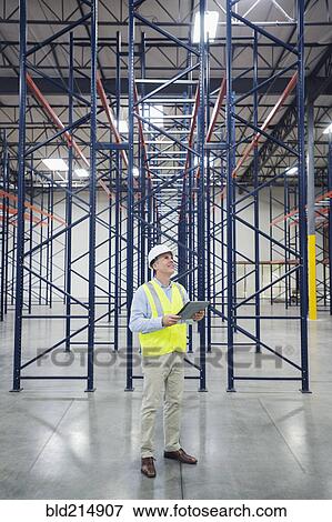 Stock Photo - Caucasian worker using digital tablet in empty warehouse. Fotosearch