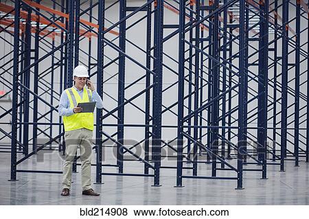 Stock Photo - Caucasian worker using digital tablet in empty warehouse. Fotosearch