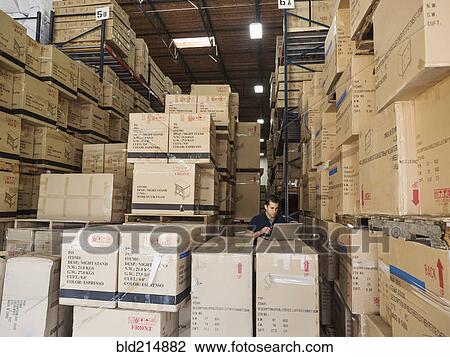 Stock Image - Caucasian worker using laptop in warehouse. Fotosearch