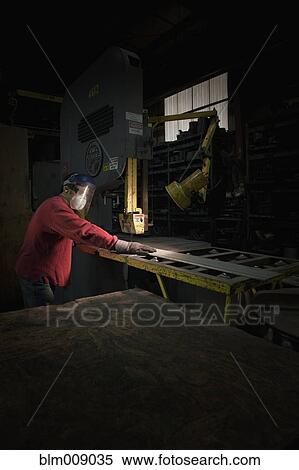 Stock Photography - Caucasian worker using saw in factory. Fotosearch