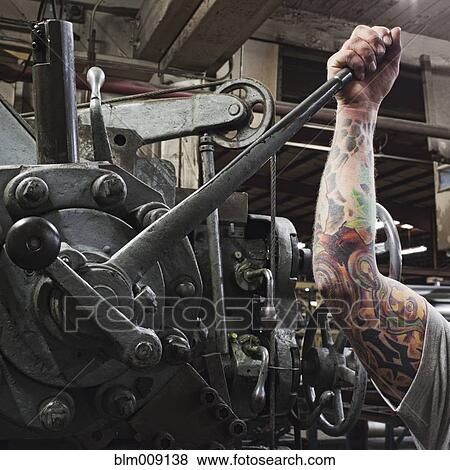 Caucasian worker with tattoos pulling lever in factory View Large Photo Image Stock Photo - Caucasian worker with tattoos pulling lever in factory. Fotosearch