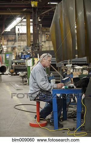 Stock Image - Caucasian worker working in factory. Fotosearch