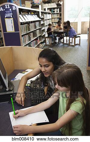 Stock Image - Children doing homework in library together. Fotosearch